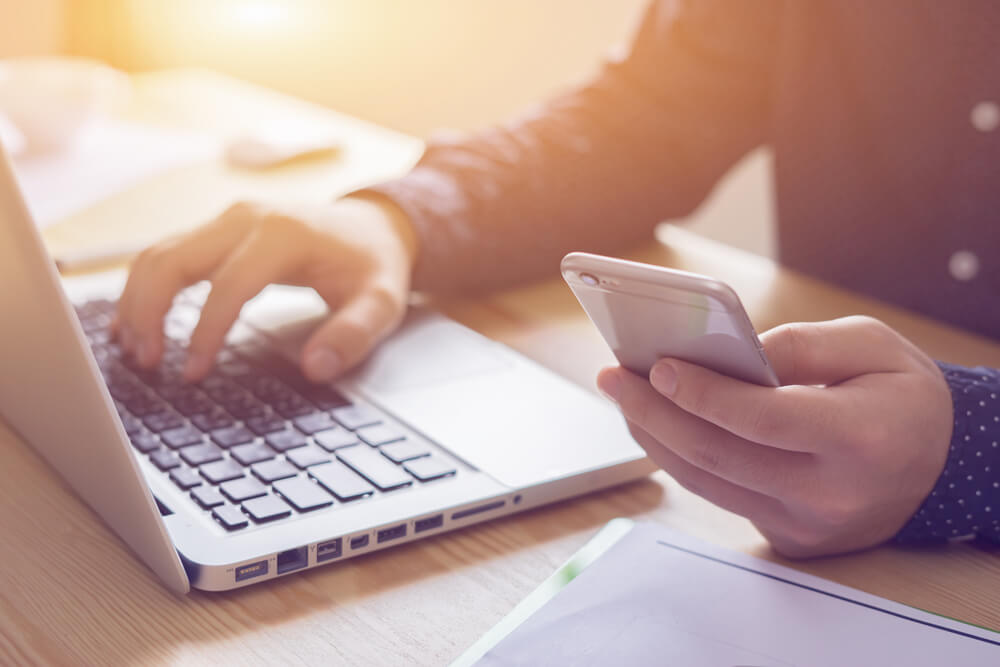 Contact us image in which a man is using a cell phone and a laptop