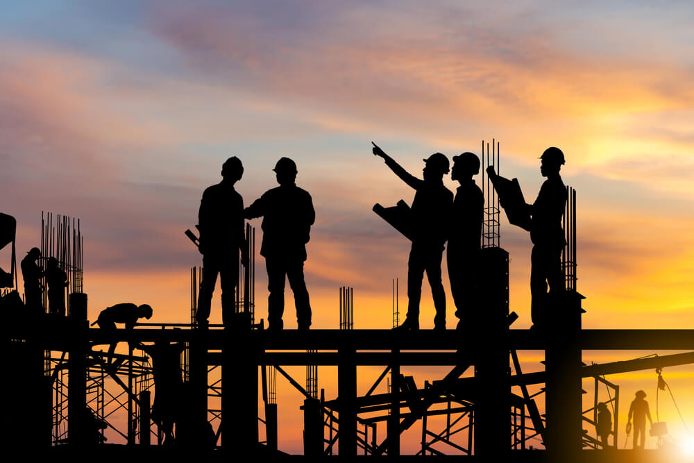 Silhouettes of construction workers at sunset.